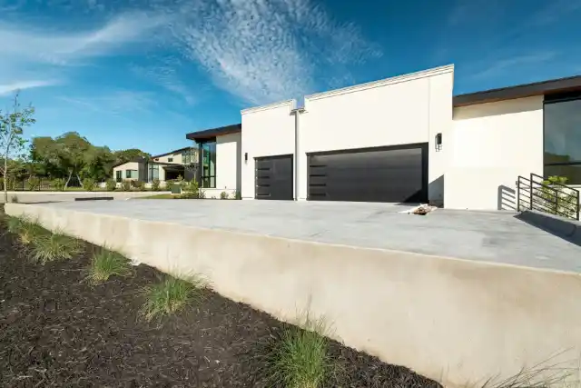 Concrete driveway leading to two black garage doors | Charleston Concrete